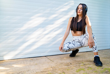 Urban strong serious female athlete posing next to abstract shadows on garage door 