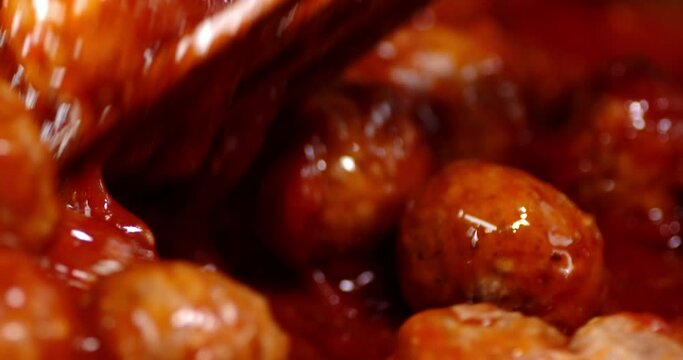 Meatballs mixed with a spatula with tomato sauce.
