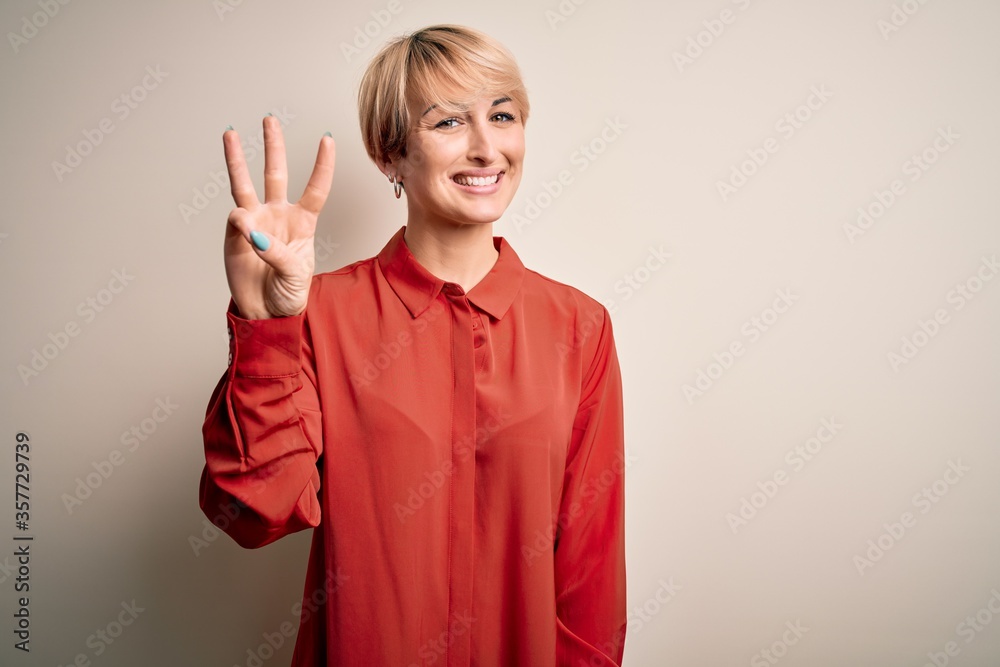 Sticker Young beautiful business blonde woman with short hair standing over isolated background showing and pointing up with fingers number three while smiling confident and happy.