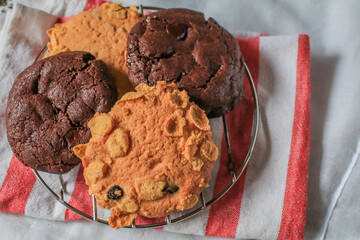 Oatmeal cookie milk cookie and chocolate chip nut cookie on grate metal red and white napkin black background.Breakfast and afternoon tea concept.