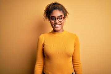 Young beautiful african american girl wearing sweater and glasses over yellow background with a...