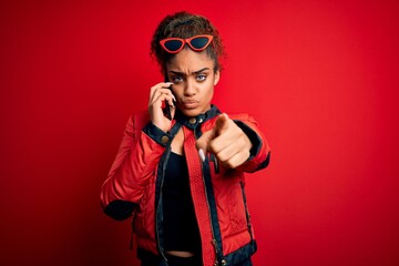 Young african american girl having conversation talking on the smartphone over red background pointing with finger to the camera and to you, hand sign, positive and confident gesture from the front