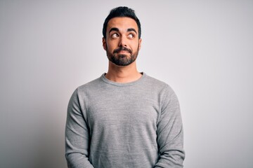 Fototapeta premium Young handsome man with beard wearing casual sweater standing over white background smiling looking to the side and staring away thinking.