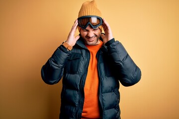 Young handsome skier man skiing wearing snow sportswear using ski goggles with hand on headache because stress. Suffering migraine.