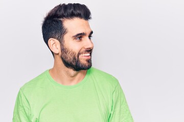 Fototapeta premium Young handsome man with beard wearing casual t-shirt looking away to side with smile on face, natural expression. laughing confident.