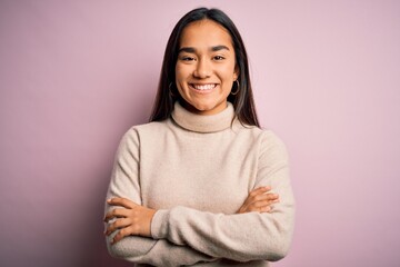 Young beautiful asian woman wearing casual turtleneck sweater over pink background happy face smiling with crossed arms looking at the camera. Positive person.