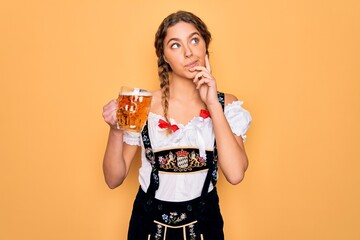 Beautiful blonde german woman with blue eyes wearing octoberfest dress drinking jar of beer serious face thinking about question, very confused idea