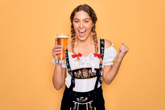 Beautiful Blonde German Woman With Blue Eyes Wearing Octoberfest Dress Drinking Glass Of Beer Screaming Proud And Celebrating Victory And Success Very Excited, Cheering Emotion