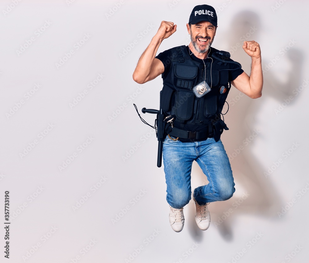 Wall mural Middle age handsome man wearing police unifrom smiling happy. Jumping with smile on face doing ok sign with fists up over isolated white background