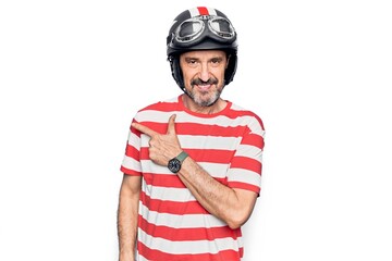 Middle age handsome motorcyclist man wearing moto helmet over isolated white background smiling cheerful pointing with hand and finger up to the side