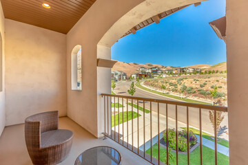 Balcony of home with wicker chair round glass table and arched window