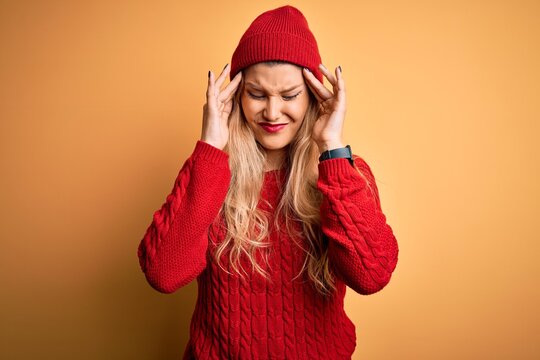 Young beautiful blonde woman wearing casual sweater and wool cap over white background with hand on headache because stress. Suffering migraine.