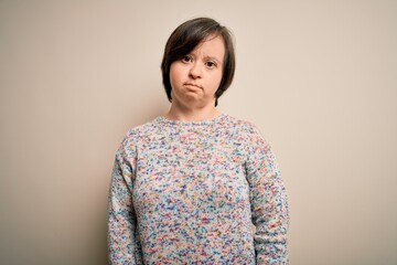 Young down syndrome woman standing over isolated background with serious expression on face. Simple and natural looking at the camera.