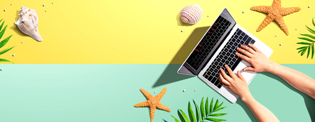 Person using a laptop computer with summer theme objects - flat lay