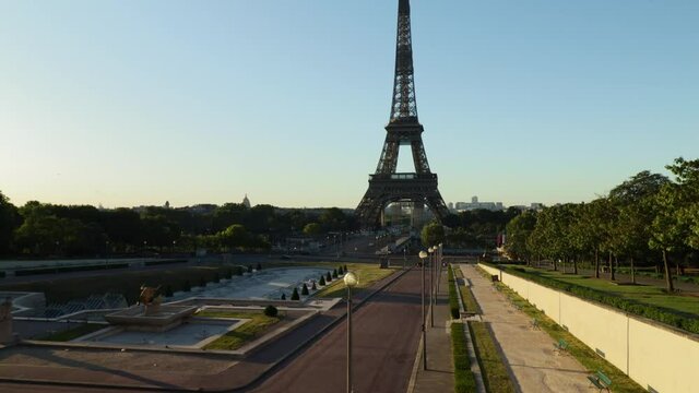 Young woman walking towards the eiffel tower and pointing with her finger, dolly in wide shot during early morning in Paris France
