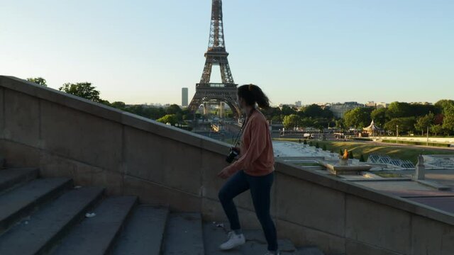 Young attractive woman walking up stairs at the trocadero with the Eiffel tower in the background during early summer morning