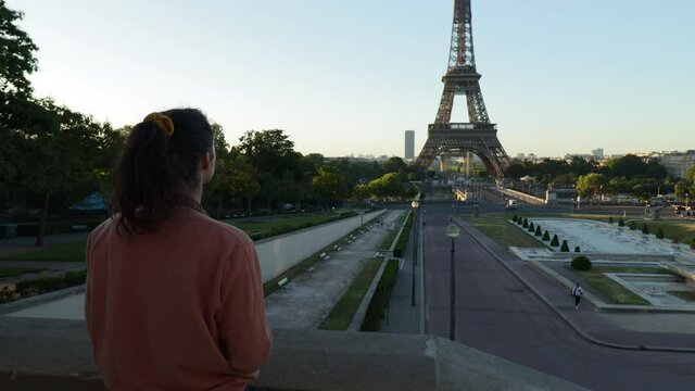 Young female photographer snapping pictures of the eiffel tower during early morning in paris France, reveal arc dolly out wide shot