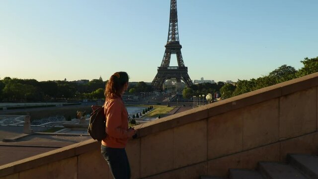 Young attractive woman walking up stairs in front of eiffel tower at trocadero in paris France during early summer morning
