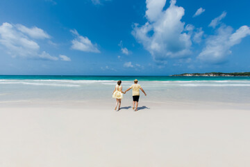 Fototapeta na wymiar Romantic couple in love enjoying beach, hugging, kissing and running on the white sandy tropical coast during honeymoon vacations. Caribbean landscape in Dominican republic Punta Cana 