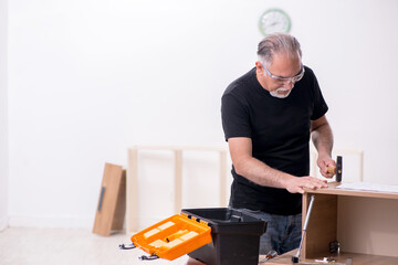 Old male carpenter working indoors