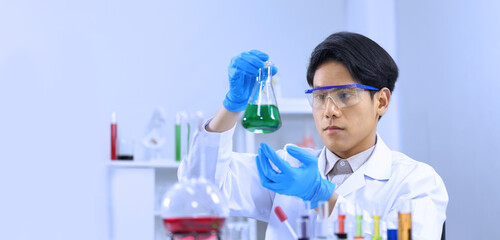 Male science researcher is studying and developing new medicine and vaccine in biochemistry to fight against virus in safety laboratory with copy space