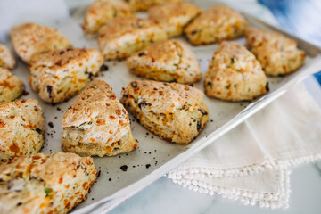 Bacon, cheddar and green onion scones on an aluminum baking sheet fresh out of the oven