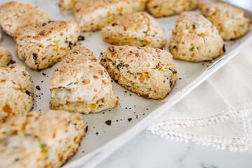 Bacon, cheddar and green onion scones on an aluminum baking sheet fresh out of the oven