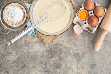 Baking cooking Ingredients for pancake, flour eggs whisk on bright grey concrete background. Top view copy space.