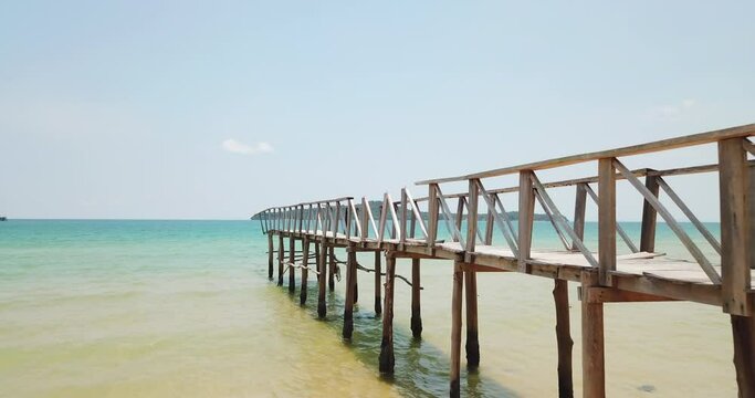 Aerial shot towards an old wooden bridge at the beach in the Gulf of Thailand in the western part of the South China Sea