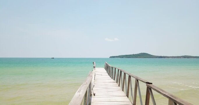 aerial tracking shot revealing an old wooden bridge at the beach in the Gulf of Thailand in the western part of the South China Sea