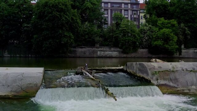 Slow rise up shot with the copter from a little Isar river dam in the inner Munich city up to the cityscape skyline of the wonderful bavarian city at springtime.