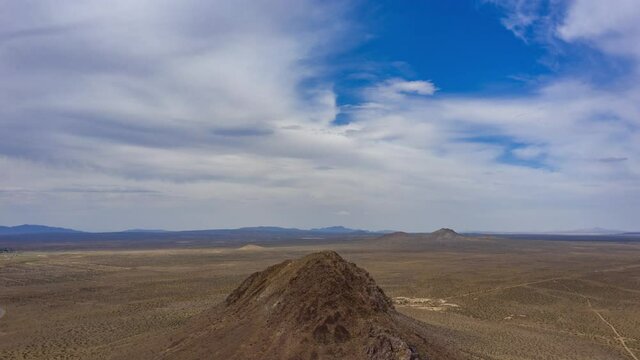 Orbiting aerial hyperlapse of a mountain top in a vast desert landscape