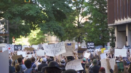 Protestors holding signs during a protest in city streets