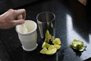 preparando uma caipirinha tipicamente  brasileira com limao, açucar e vodka juntamente com a...