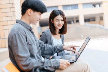  teenager sitting on stair at college campus with school books and a laptop computer doing homework. Education concept.