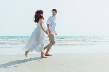 Fototapeta na wymiar Romantic couple holding hands running and walking on beach. Man and woman in love. People travel concept.
