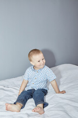 Fototapeta premium Toddler in a shirt and pants on a gray background