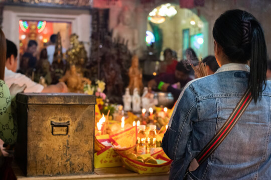 Phnom Penh, Cambodia; February 2020: Woman praying at chinese temple Neak Ta Preah Chao, Wat Phnom. Incense bars burning with smoke. This temple is the central point of Phnom Penh, Cambodia