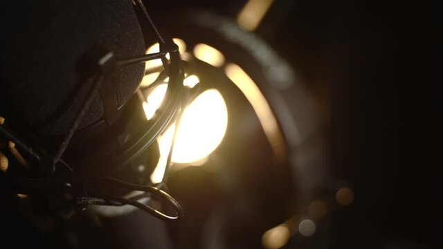 Slow pan of a podcast mic with backlighting for cinematic flare