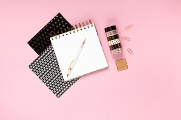 Notepad and notebooks with stationery. Golden, white, pink and black stationery back to school concept.