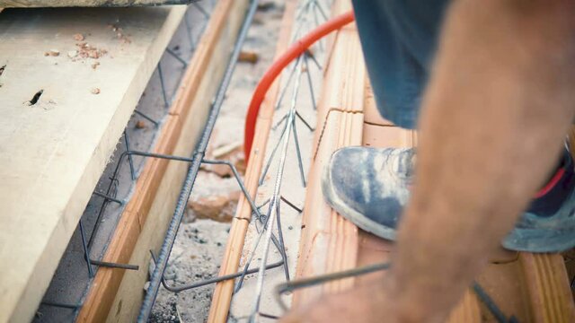 Closeup shot of bar bender hands fixing steel reinforcement bars with binding wire