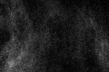 Abstract splashes of water on black background. Freeze motion of white particles. Rain, snow overlay texture.