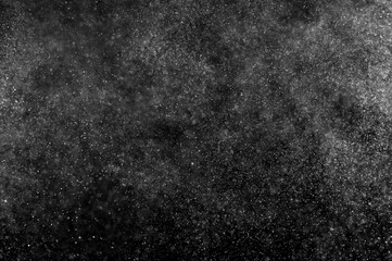 Abstract splashes of water on black background. Freeze motion of white particles. Rain, snow overlay texture.