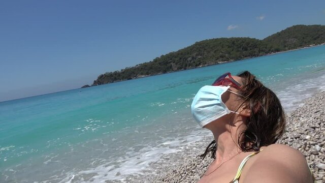 Oludeniz, Fethiye, Turkey - 11th of June 2020: 4K Woman makes selfie wearing face mask on the beach
