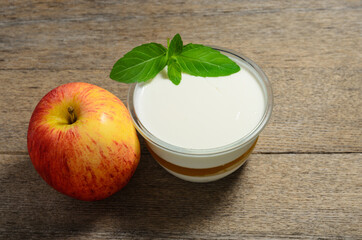 Apple dessert with mint leaves and a ripe red Apple on the background of old rustic ash planks. Selective focus.