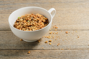 Muesli in a white bowl against the background of old village ash planks. Selective focus.