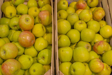 Juicy, round, solid apples with a shiny green skin and rarely with red streaks, lying in wooden boxes-trays, put up for sale. Concept: healthy, organic, nutritious food for life.