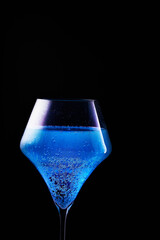 Blue drink is poured into a glass. Black background.