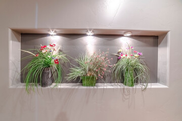 Three flower arrangements in a wall alcove