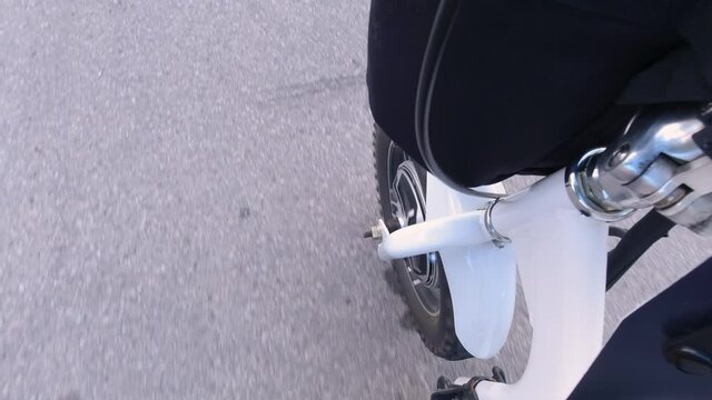 Riding electric bicycle on the city streets. Camera view to the power motor or electro motor of the wheel. Natural lighting. Close up.